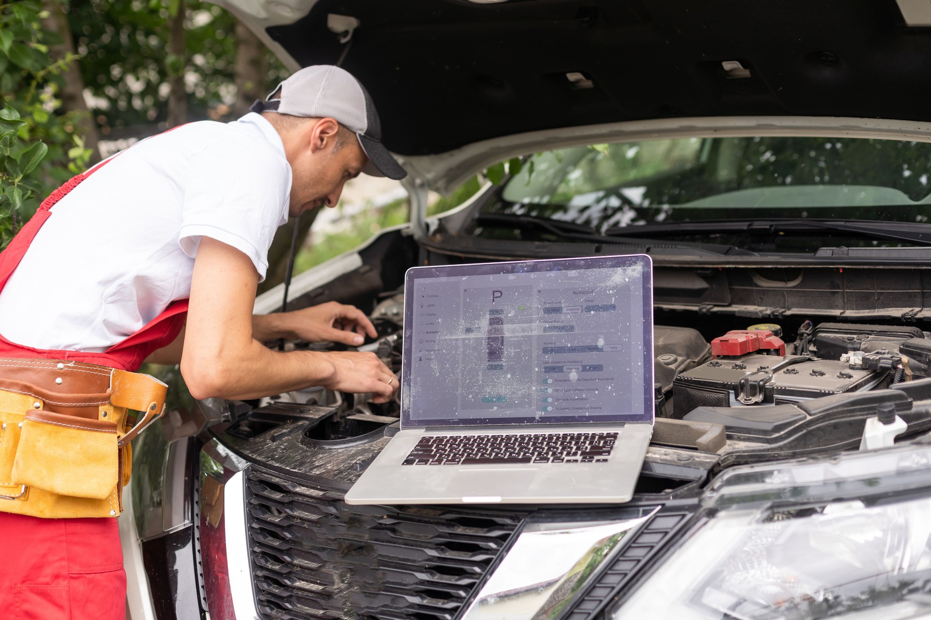 Kfz-Mechaniker offene Motorhaube, um das Autoproblemsystem per Laptop für die Wartung zu reparieren und zu überprüfen und in der Garage zu reparieren