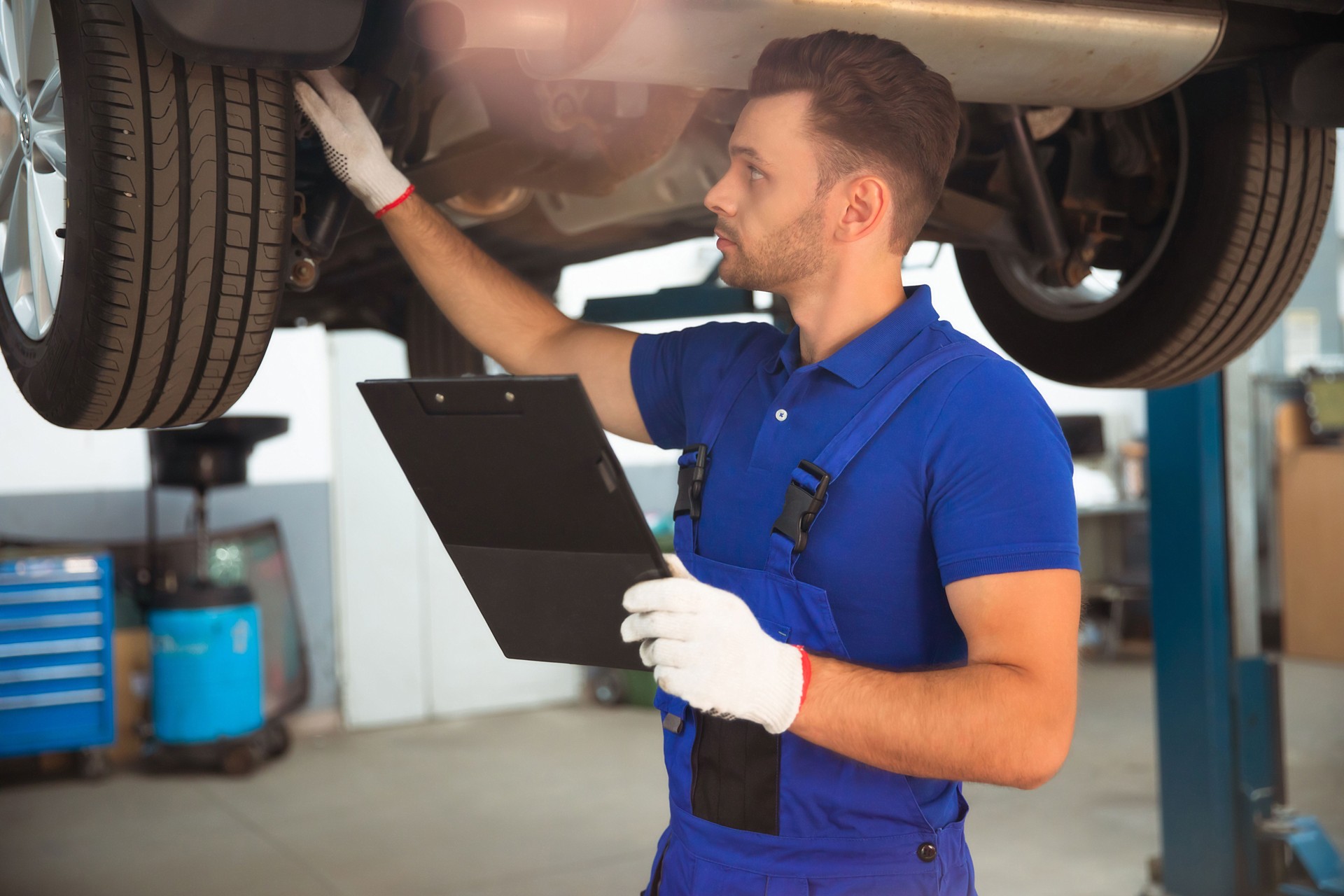 Selbstbewusster und konzentrierter junger und erfahrener Autoreparaturspezialist mit einem Tablet in der Hand inspiziert und diagnostizieren das Auto auf Pannen